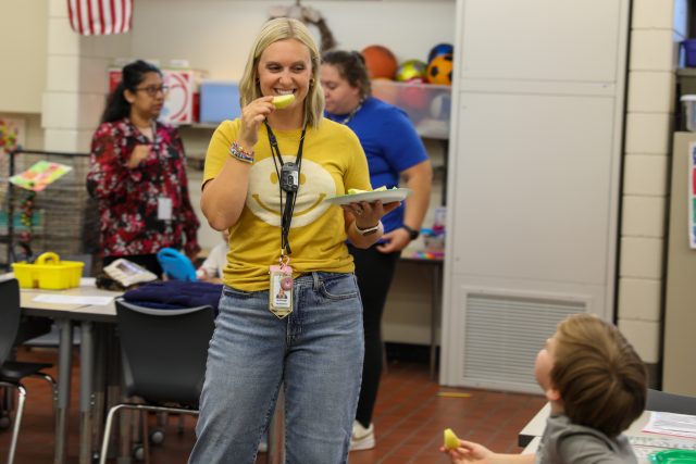 Teacher tries an apple slice during the apple tasting activity.