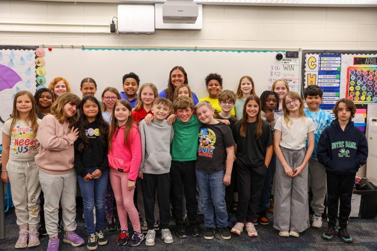 Group of students posing in front of a classroom chalkboard.