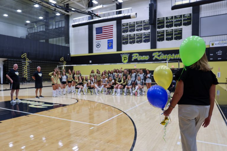 Team of cheerleaders posing for a group photo in gymnasium.